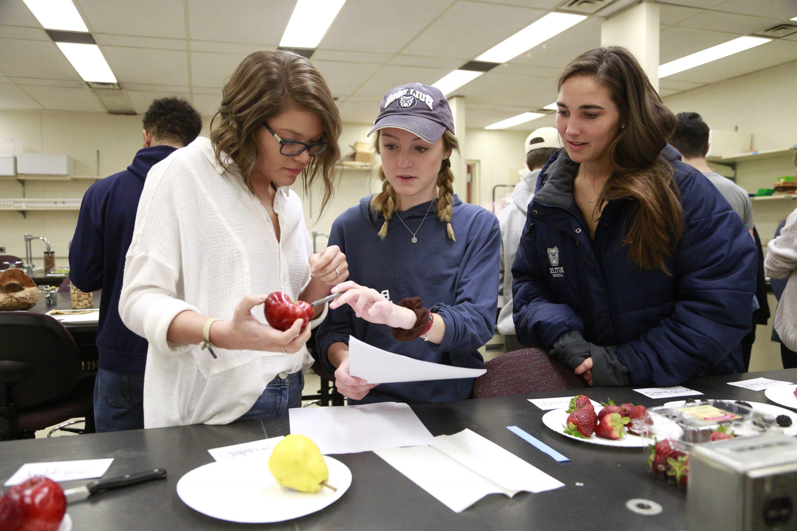 Three female students in a science laboratory performing an experiment.